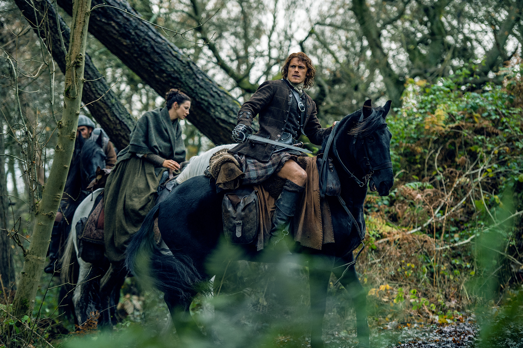 Of course, they look completely fabulous while doing it. (Left, Caitriona Balfe as Claire Fraser. Right, Sam Heughan as Jamie Fraser. They are riding horses through the woods.)