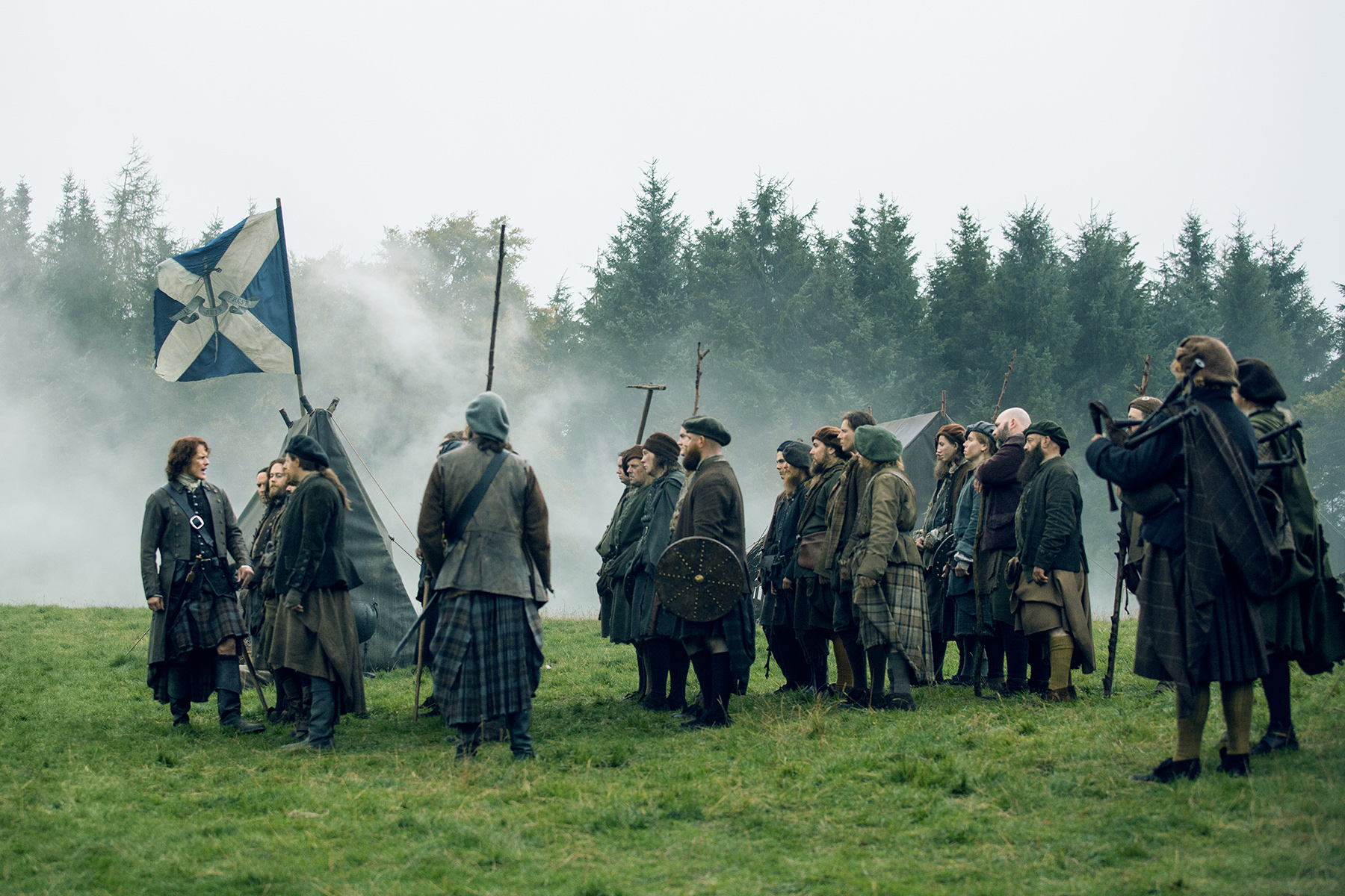 Let's get down to business. To defeat. THE BRITISH. (On left, Sam Heughan as Jamie Fraser instructing his new troops.)