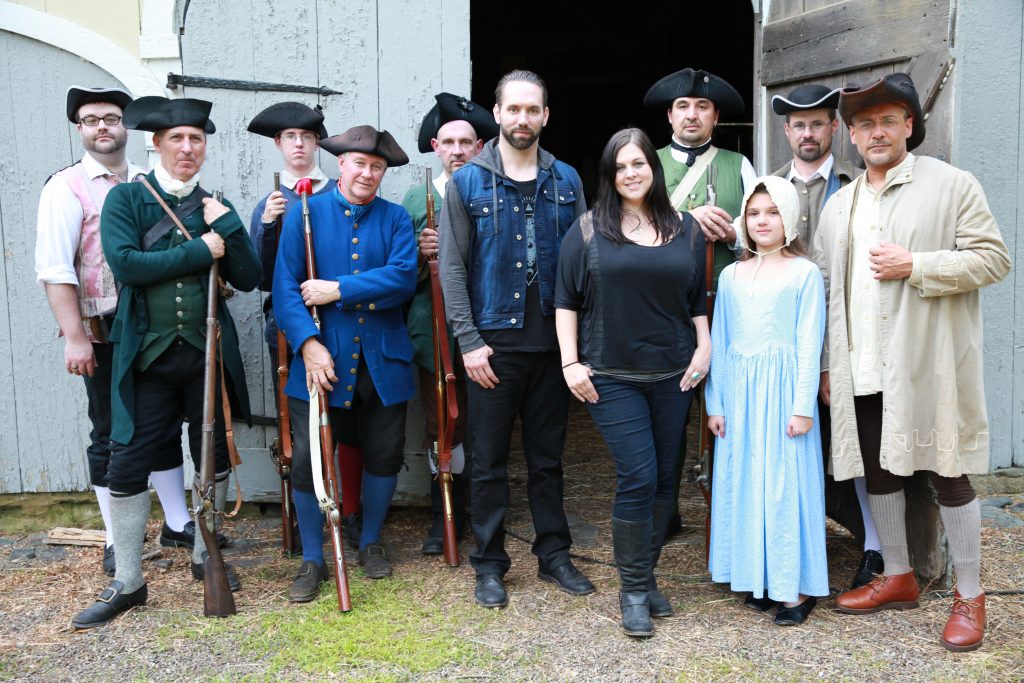 Nick Groff and Katrina Weidman stand with actors in Revolutionary War clothing, ready to reenact the history of Oliver House.